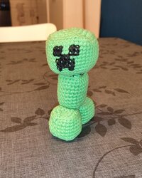 Le Creeper de Minecraft au crochet terminé, debout sur une table, face à l'objectif